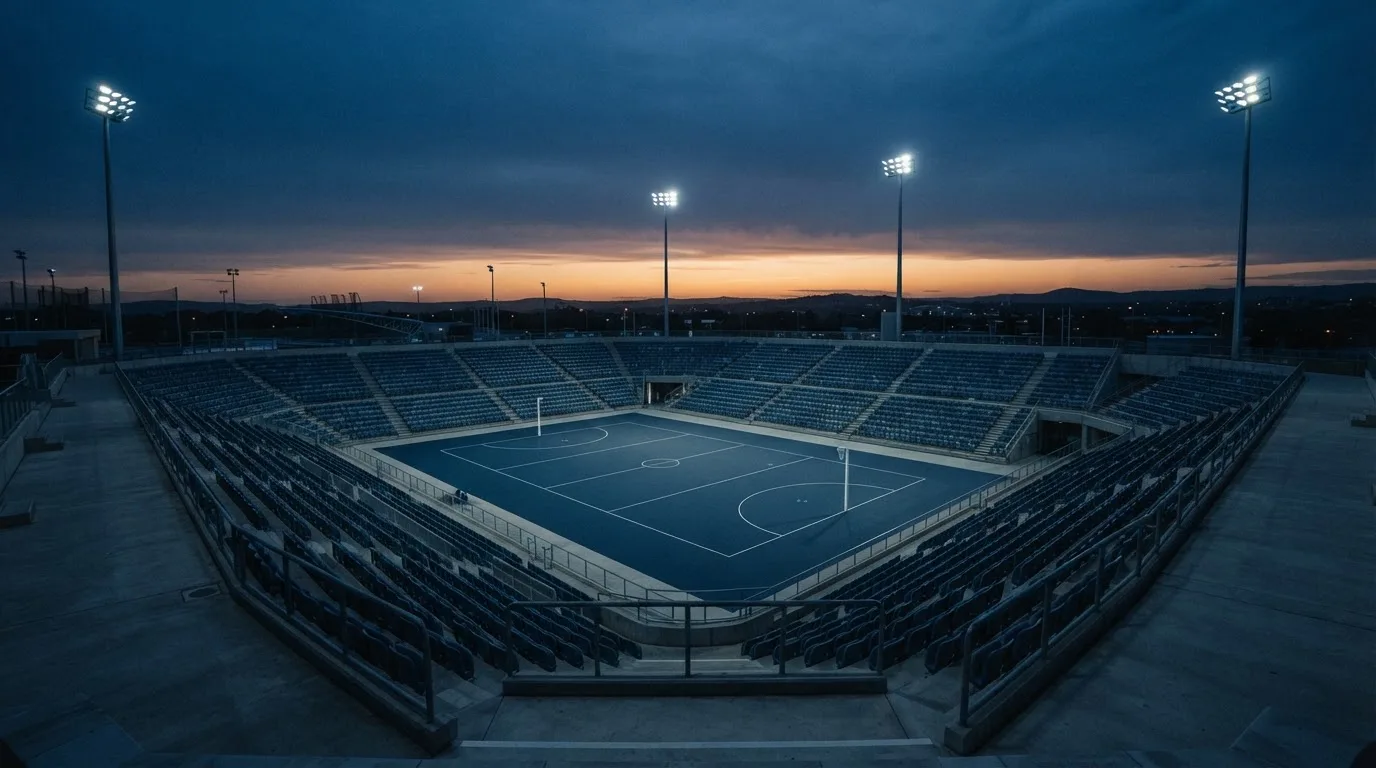 An empty football stadium with floodlight masts at dusk