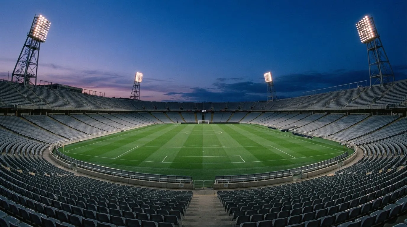 An empty football stadium with floodlight masts at dusk