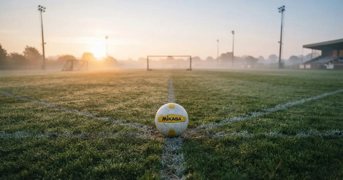 A ball on the centre spot of a grass pitch in morning light