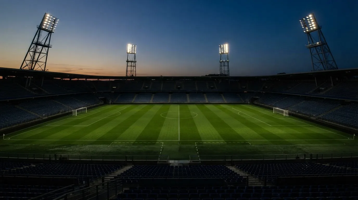 An empty football stadium with floodlight masts at dusk