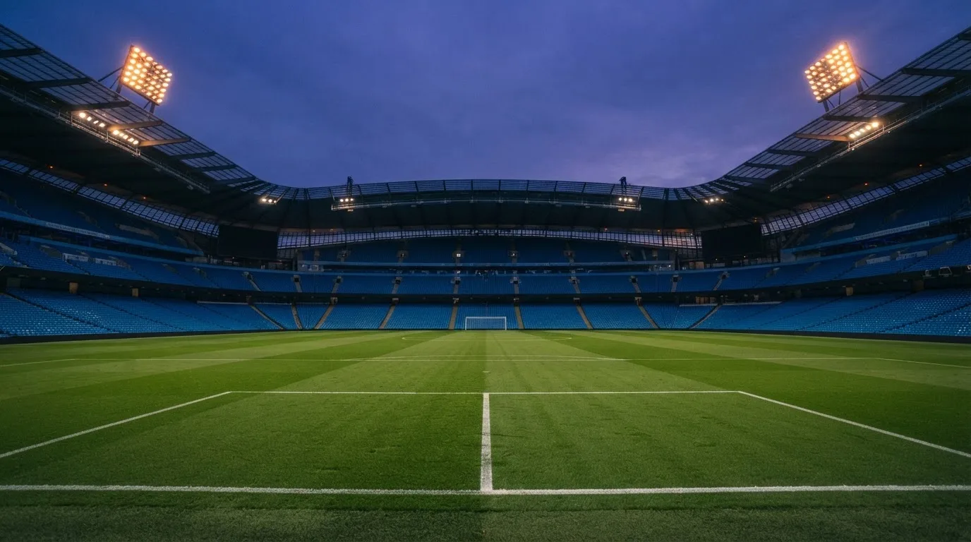 An empty football stadium with floodlight masts at dusk