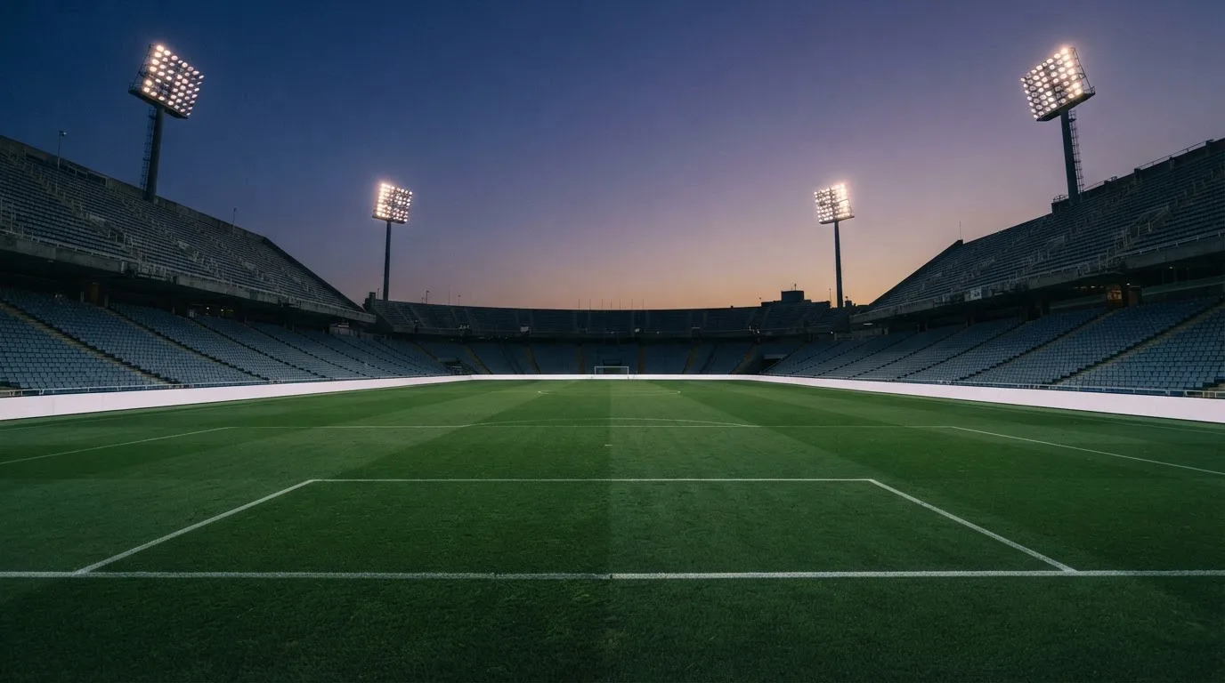 An empty football stadium with floodlight masts at dusk