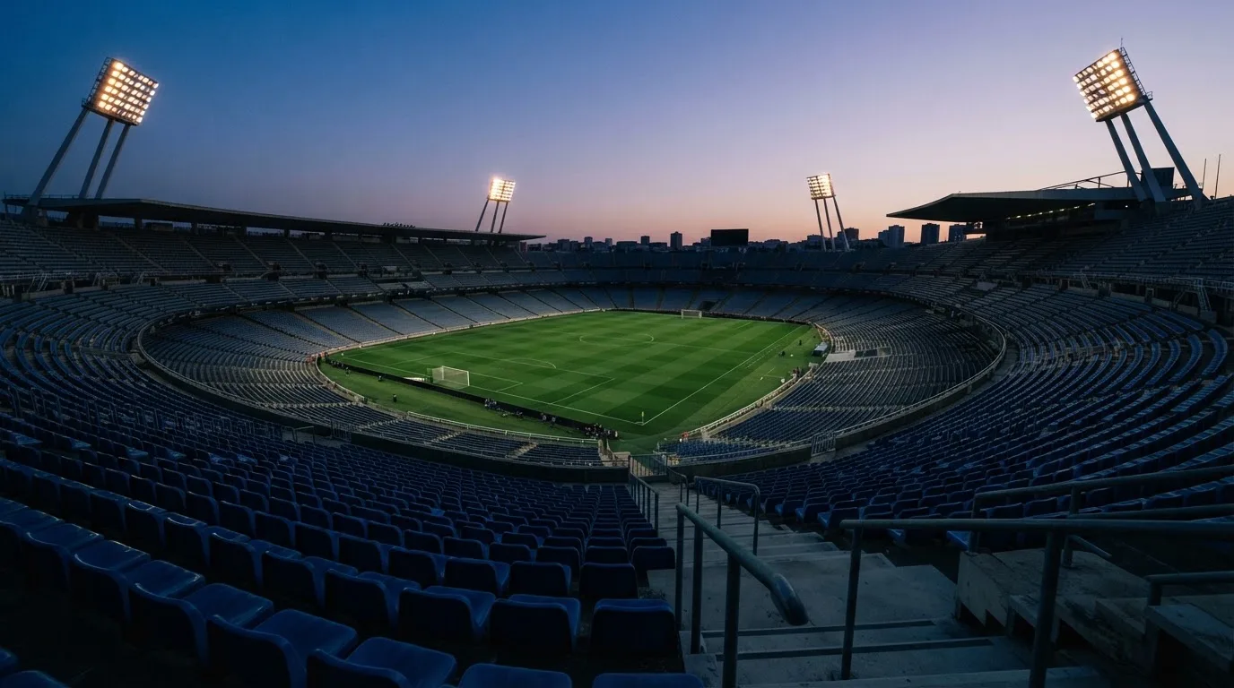 An empty football stadium with floodlight masts at dusk