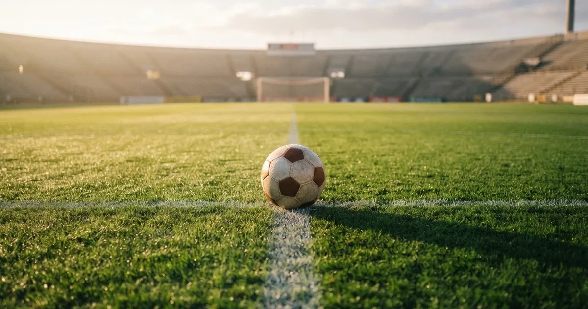A ball on the centre spot of a grass pitch in morning light