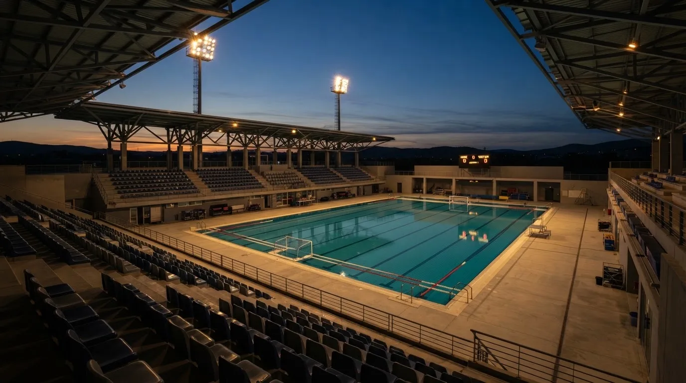 An empty football stadium with floodlight masts at dusk